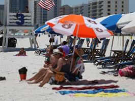 A group of people on a beach with umbrellas and chairs.