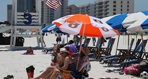 A group of people on a beach with umbrellas and chairs.