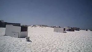 A group of beach huts on a white sand beach.