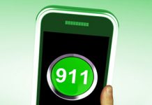 A person holding up a green phone with the number 911 on it.