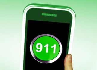A person holding up a green phone with the number 911 on it.