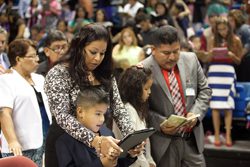 A woman and a child looking at a tablet in front of a crowd.