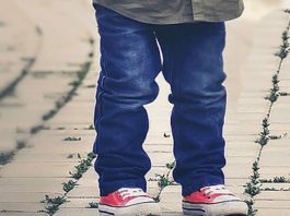 A little boy is standing on a brick walkway.