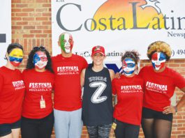 A group of people with painted faces posing in front of a sign.