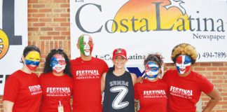 A group of people with painted faces posing in front of a sign.