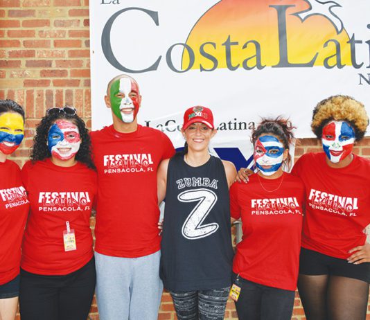 A group of people with painted faces posing in front of a sign.