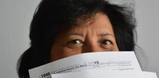 A woman is holding up a stack of tax forms.