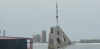 artificial reef modules being dropped into water with crane