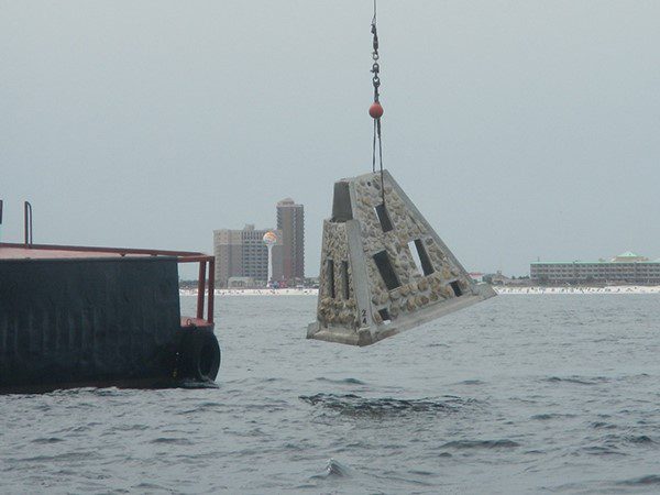 artificial reef modules being dropped into water with crane
