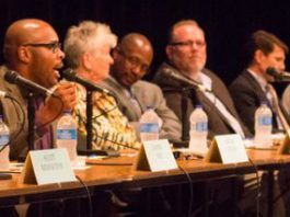 A group of people sitting at a table with microphones.