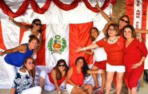 Gropu of women standing next to a Peruvian flag
