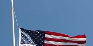 An american flag flies against a blue sky.