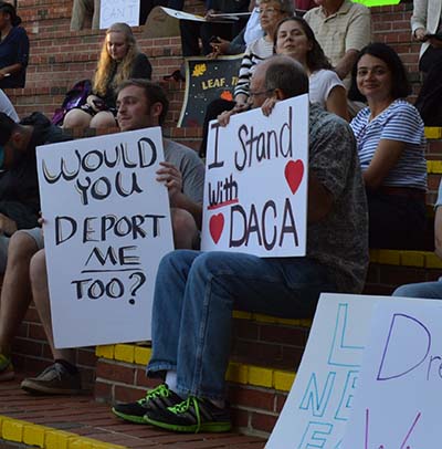 A group of people sitting on steps holding signs.
