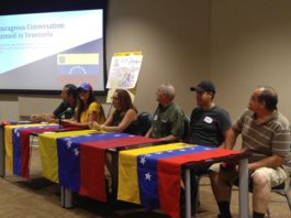 Venezuelan nationals sitting behind tables drapped with the Venezuelan flag