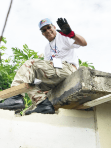 Man repairing roof and waving to camera