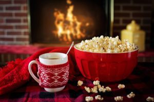 hot chocolate, popcorn on a table in front of a burning fireplace