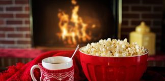 hot chocolate, popcorn on a table in front of a burning fireplace