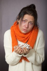 woman with flu holding pills