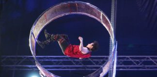 A man doing a circus act on a metal ring.