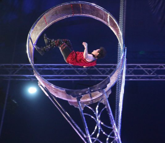 A man doing a circus act on a metal ring.