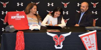 Athlete signs contract with Spanish Fort Athletics docorated table and backdrop, parents at side