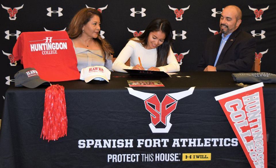 Athlete signs contract with Spanish Fort Athletics docorated table and backdrop, parents at side