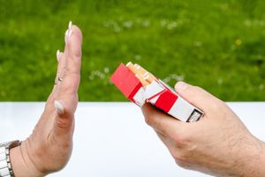 hand rejecting another hand offering cigaretts