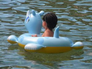 Child sitting on inflatable toy floating in the water