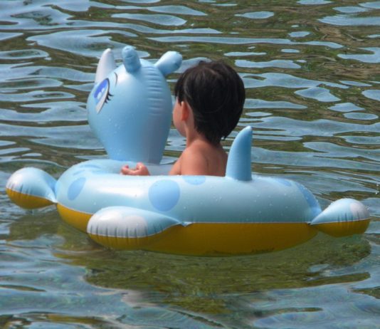 Child sitting on inflatable toy floating in the water