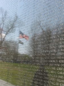 Names engraved into Vietname Memorial Wall with reflection of American flag