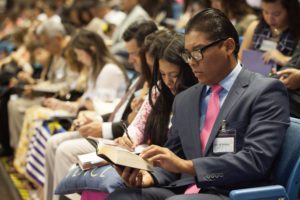 a row of people reading the bible and writing notes