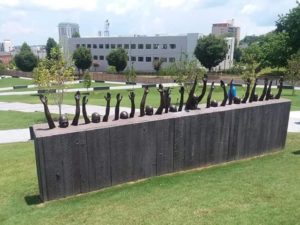 statue of multiple people in a line holding up their hands