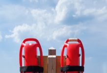 Two life preservers on a wooden post at the beach.