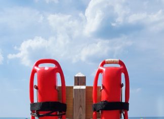 Two life preservers on a wooden post at the beach.