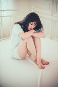 girl on bed hugging her legs