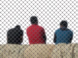 three men sitting inside a fence