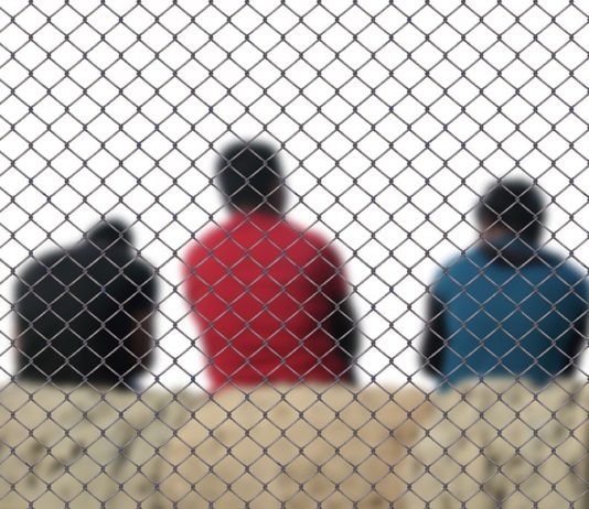 three men sitting inside a fence