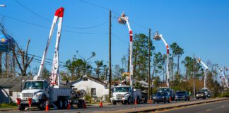 Utility trucks on road with bucket lifts extended