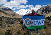 girl holding UWF flag on top of mountain