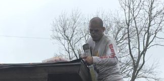 Man standing on ladder repairing roof