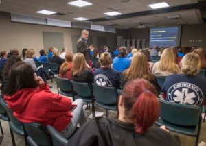 Man speaking to dozens of people in audience