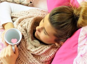 woman in bed with cup of hot water