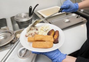 yuca, plantains and cole slaw being served on a paper plate