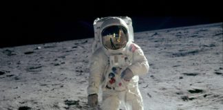 A man in a white suit standing on the moon.