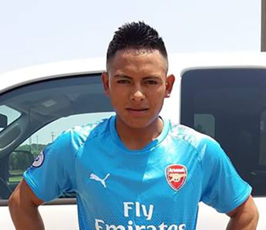 A soccer player posing in front of a car.
