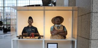 Two wooden statues are on display in a glass case.