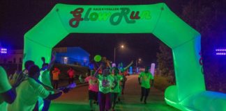 A group of people running through a glow run at night.