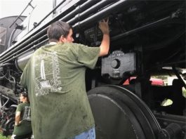 A man is working on a black steam locomotive.