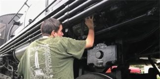 A man is working on a black steam locomotive.