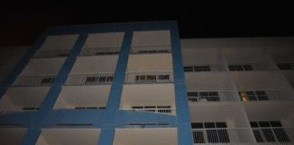 A blue and white building with balconies at night.